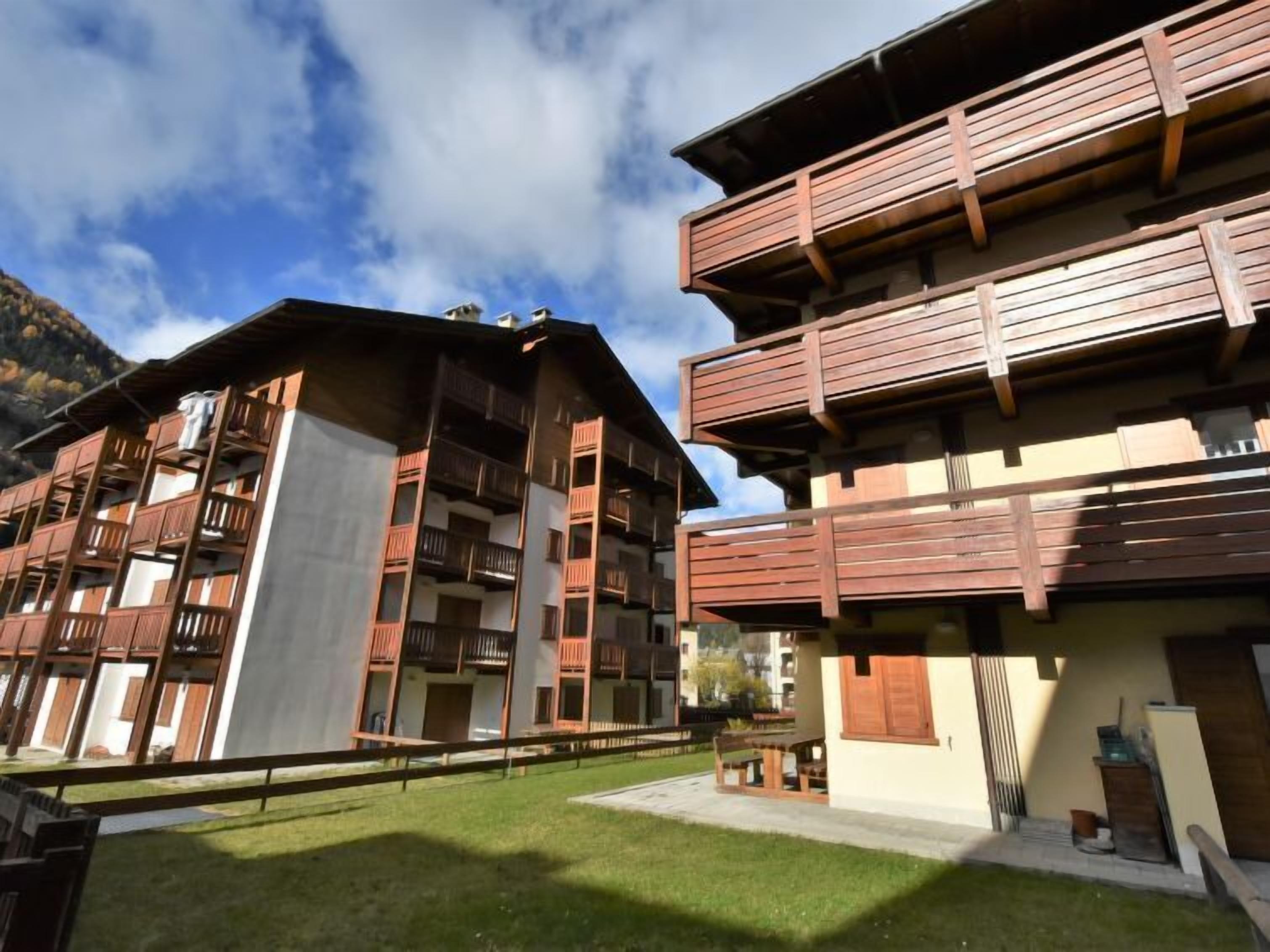A modern multi-story building with wooden balconies and a grassy courtyard.