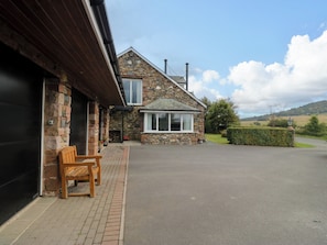 A stone house with a garage, a wooden bench, and a clear view of the countryside. - Sherriff (Penrith)