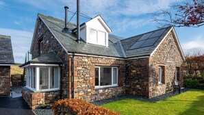 Une maison en pierre avec un toit en pente, deux cheminées et une petite fenêtre.