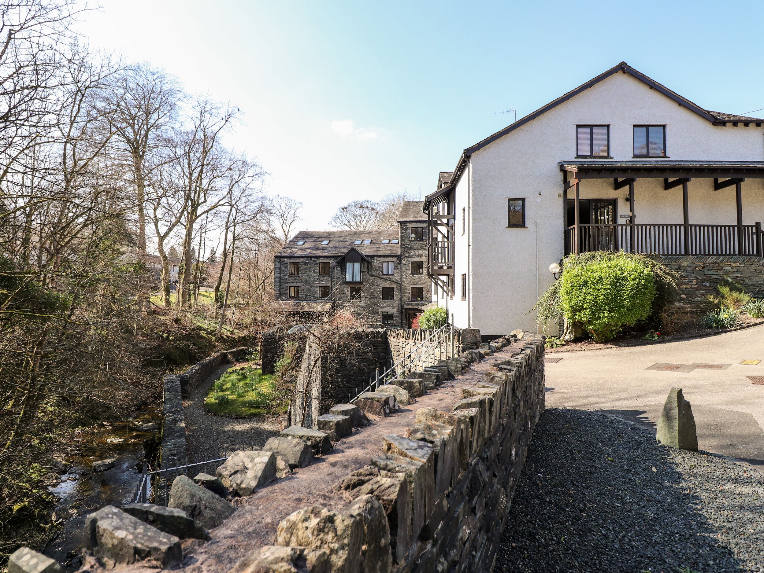 A stone bridge leading to a white building with a balcony.