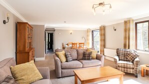 A cozy living room with a sofa set, a wooden coffee table, and a dining area with chairs and a table. - Ghyll View (Ambleside)