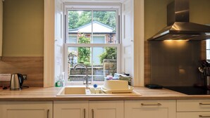 Eine Küche mit Fenster, einer Edelstahl-Dunstabzugshaube und einem Spülbecken.