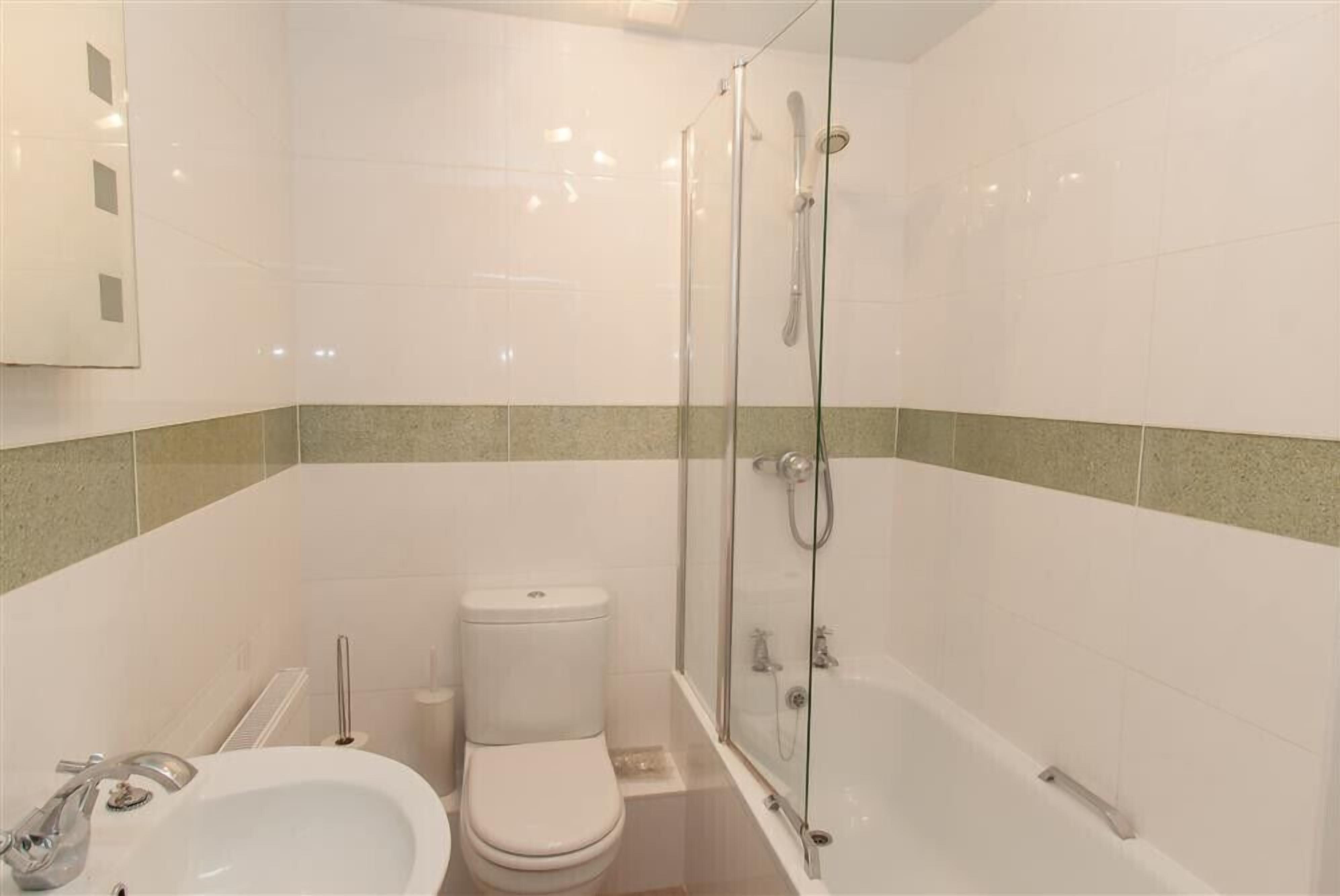 A modern bathroom with a glass-enclosed shower, a white sink, and a toilet.