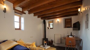 Ein gemütliches Wohnzimmer mit einer Couch, einem Kamin, einem Essbereich mit Tisch und Stühlen sowie einer Küchenzeile mit Herd und Schränken.