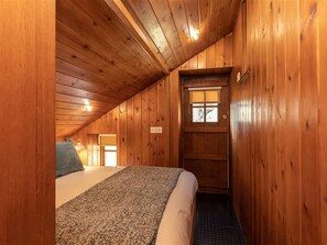 Um quarto de cabana de madeira acolhedor, com uma cama, uma janela com vista e uma porta.