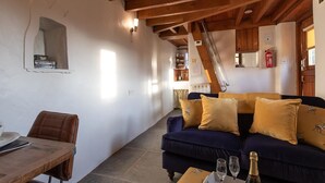 Ein gemütliches Wohnzimmer mit einem dunkelblauen Sofa, einem Holzesstisch und einer Treppe, die zu einer oberen Ebene führt.