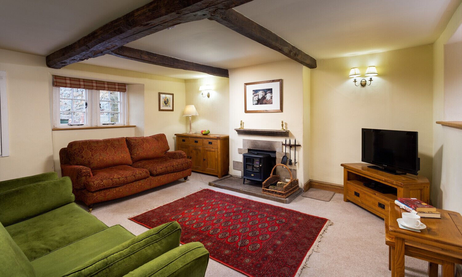A cozy living room with a fireplace, a sofa, a green armchair, and a television on a wooden stand.