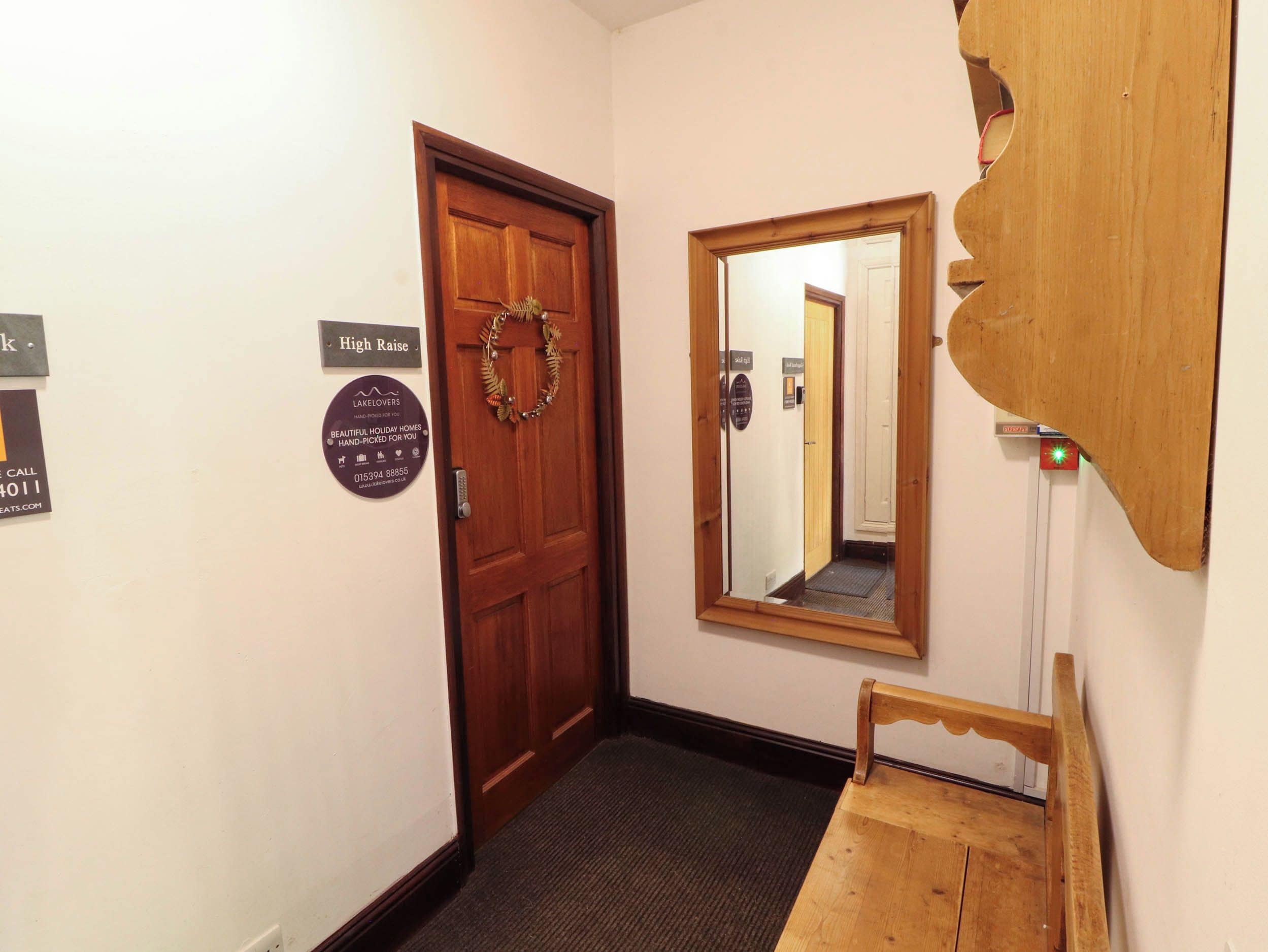 A hallway with a wooden door, a mirror, and a small wooden bench.