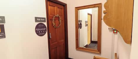 A hallway with a wooden door, a mirror, and a small wooden bench.