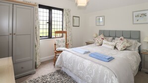 A bedroom with a bed, a chair, a wardrobe, a window, and a bedside table. - Larch Cottage (Ambleside)