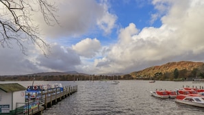 A pier with boats docked, a sign indicating 'Pier 2', and a mountainous backdrop.