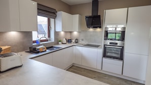 A modern kitchen with white cabinets, a built-in oven, and a window with a view of the outside.