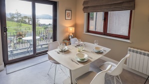 A dining area with a table set for four, a view of a balcony, and a radiator on the wall.