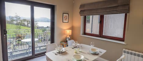 A dining area with a table set for four, a view of a balcony, and a radiator on the wall.