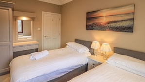 A hotel room with two beds, a bathroom, a painting, and a ceiling light.