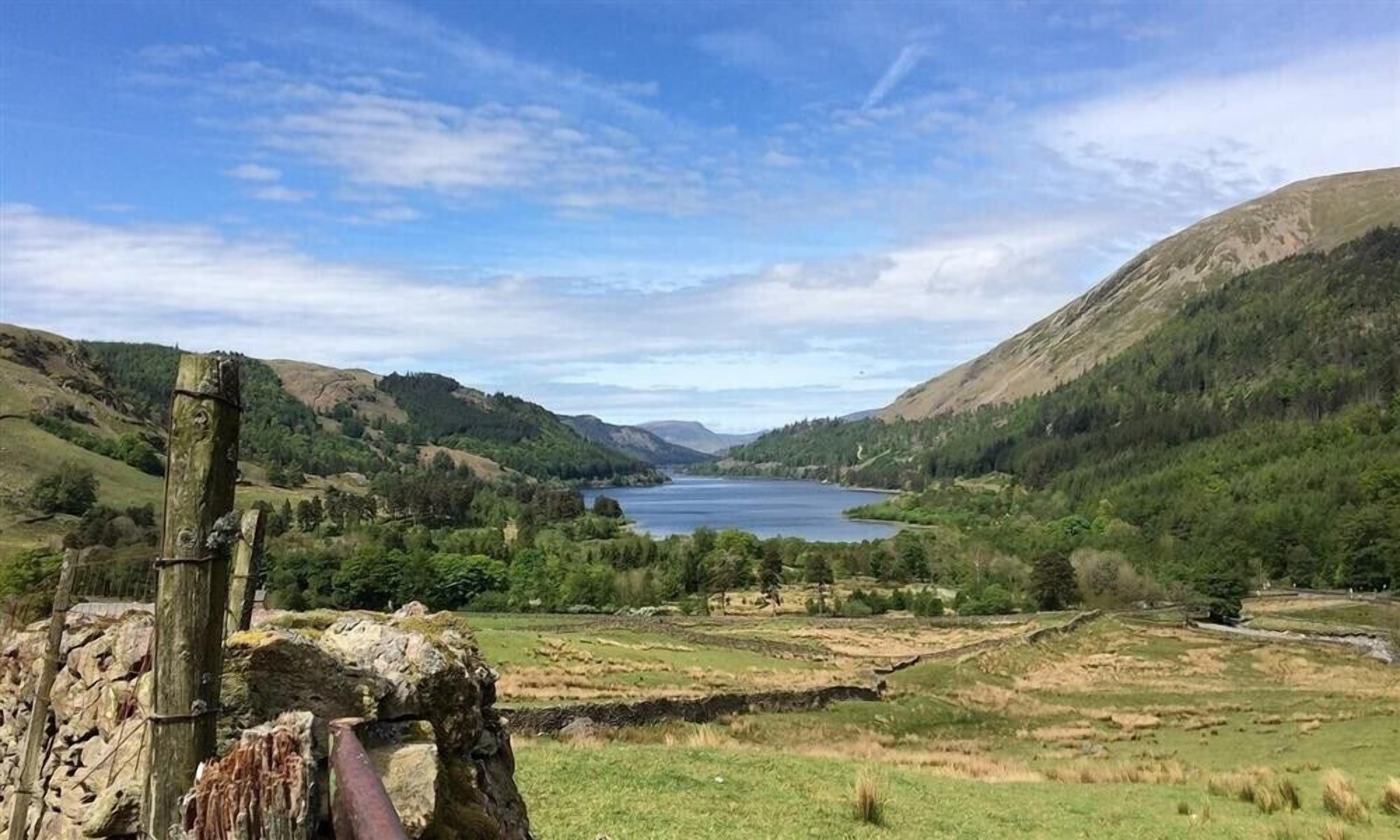 A scenic landscape with a lake, hills, and a wooden structure.