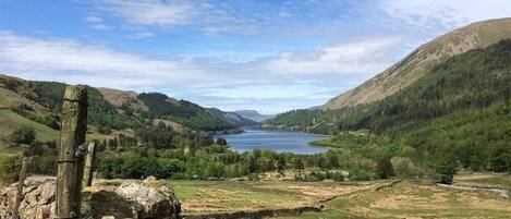 A scenic landscape with a lake, hills, and a wooden structure.