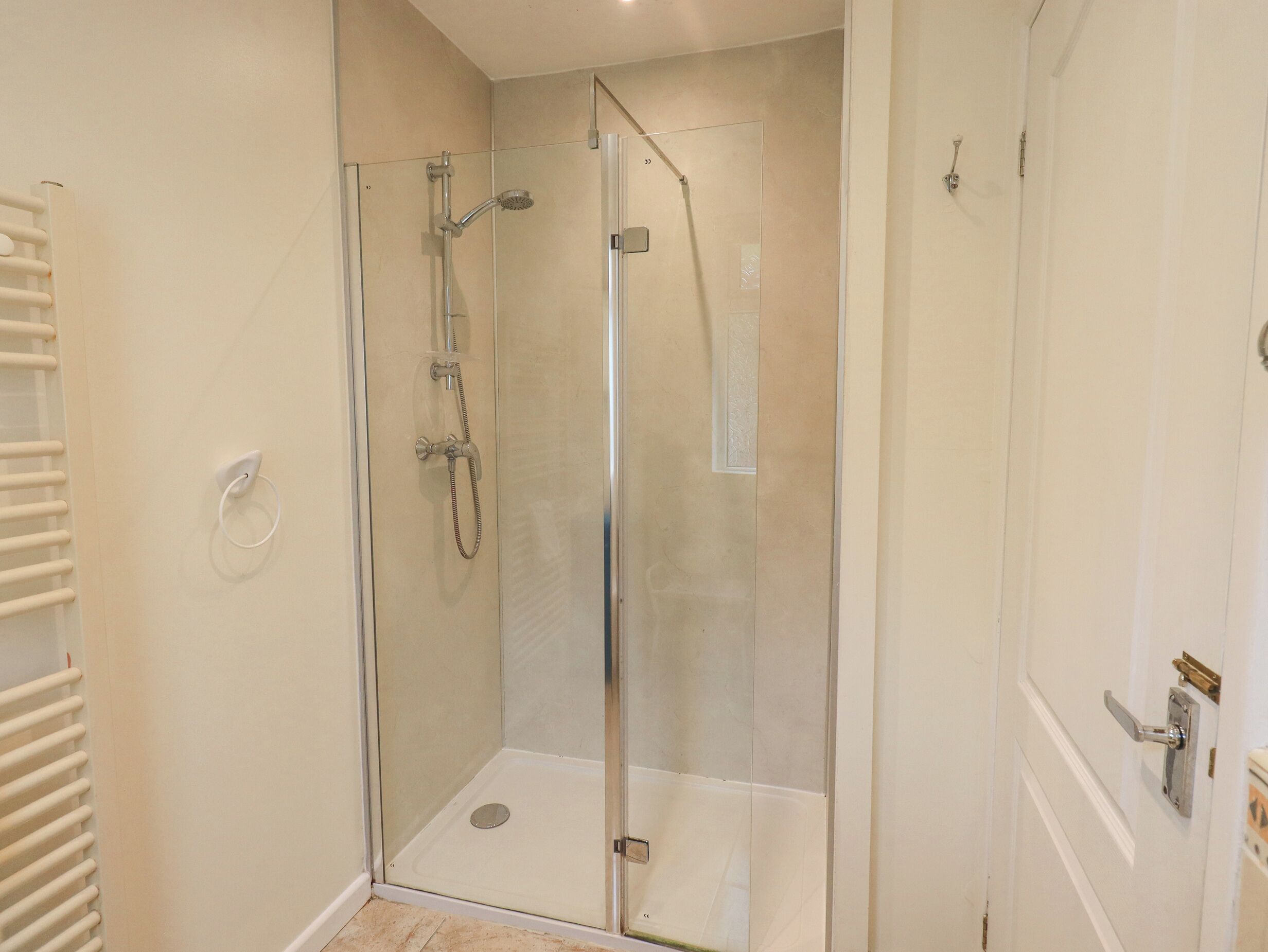 A glass-enclosed shower area with a showerhead, handheld shower, and a control panel.