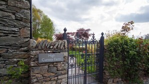 Un mur de pierres sur lequel est apposée une plaque indiquant « High Cunsy Farm », et une porte en fer forgé noire.