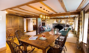 A dining area with a wooden table, chairs, and a fireplace in the background.