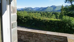 A stone wall with a view of mountains and greenery. - Dancing Beck Cottage (Keswick)