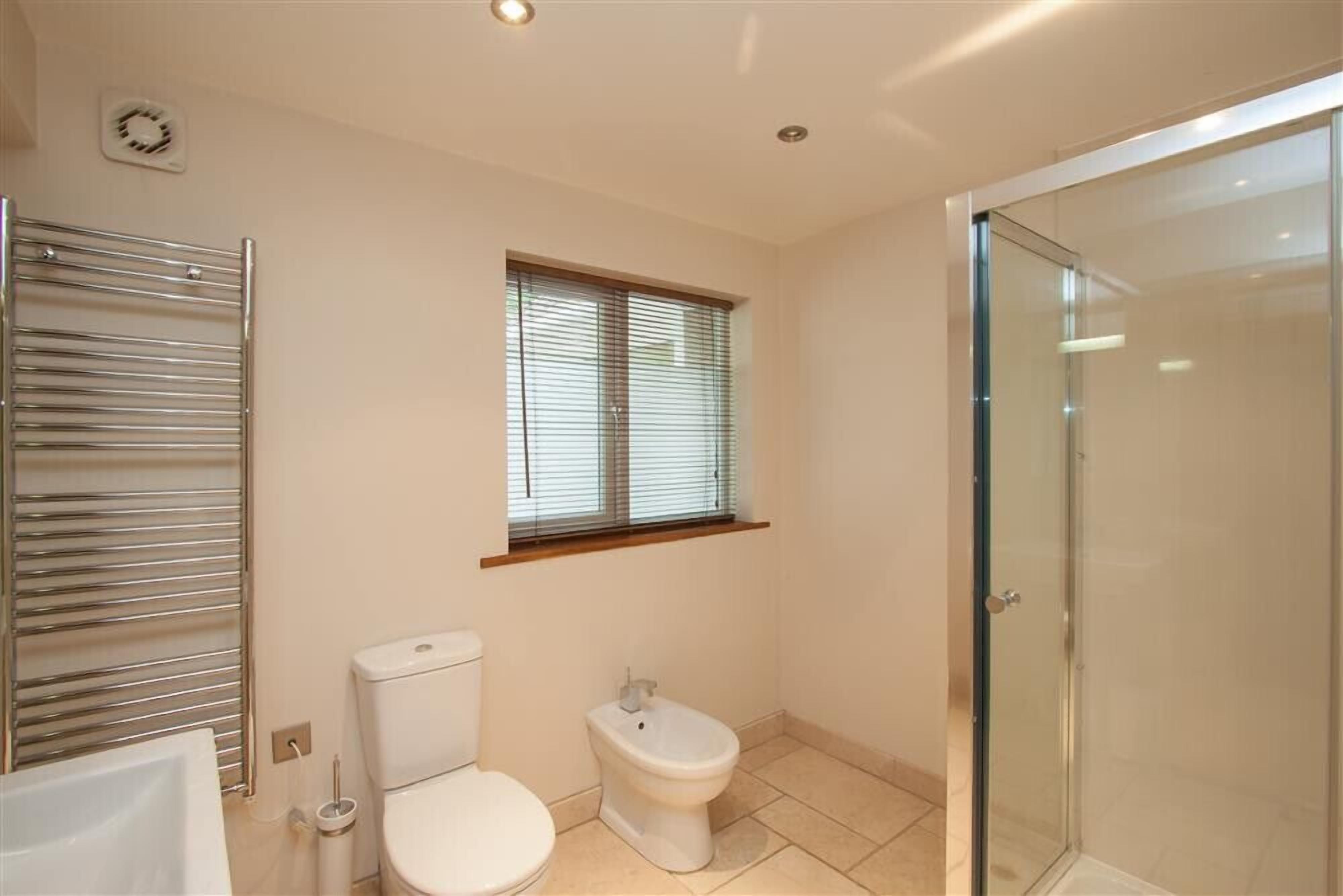 A bathroom with a toilet, bidet, and glass shower enclosure.