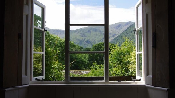 A room with a large window offering a view of a mountainous landscape. - Thomas Grove House (Penrith)