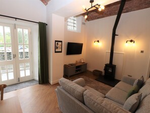 A living room with a sofa, a fireplace, a TV, and a window with curtains. - Fair Cop (Ambleside)