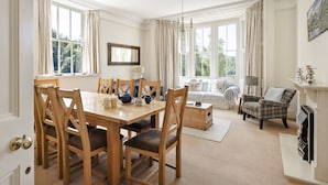 A spacious dining area with a wooden table and chairs, a sofa, and a fireplace. - Wetherlam (Ambleside)