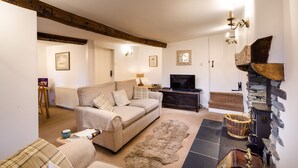 Una sala de estar acogedora con un sofá, televisor, chimenea y una pared de piedra.