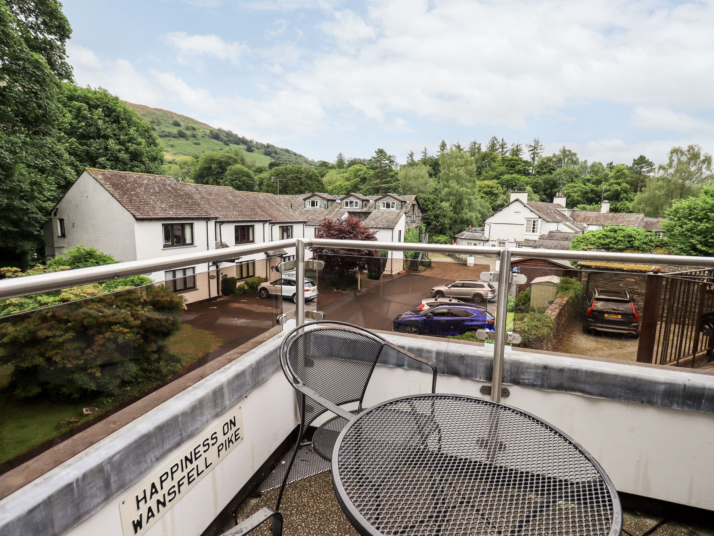 Een balkon met metalen stoelen en een bord waarop staat: 'Geluk op Wansfell Pike'.