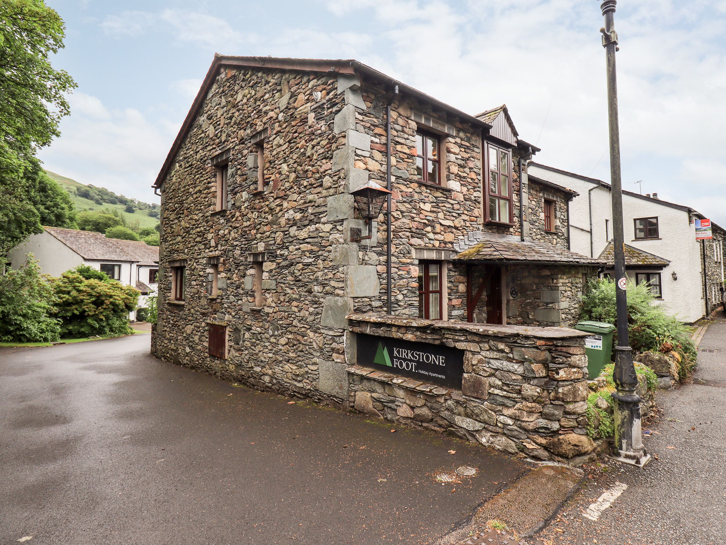 Un edificio de piedra con un letrero que dice 'Kirkstone Foot Holiday Apartments'.