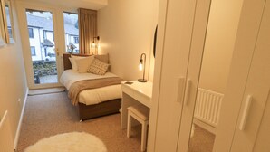 A bedroom with a bed, bedside table, lamp, and a view of the outside. - Chapelside Cottage (Ambleside)