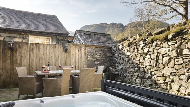 A hot tub area with wicker chairs and a stone wall. - Yew Tree Farm (Coniston)