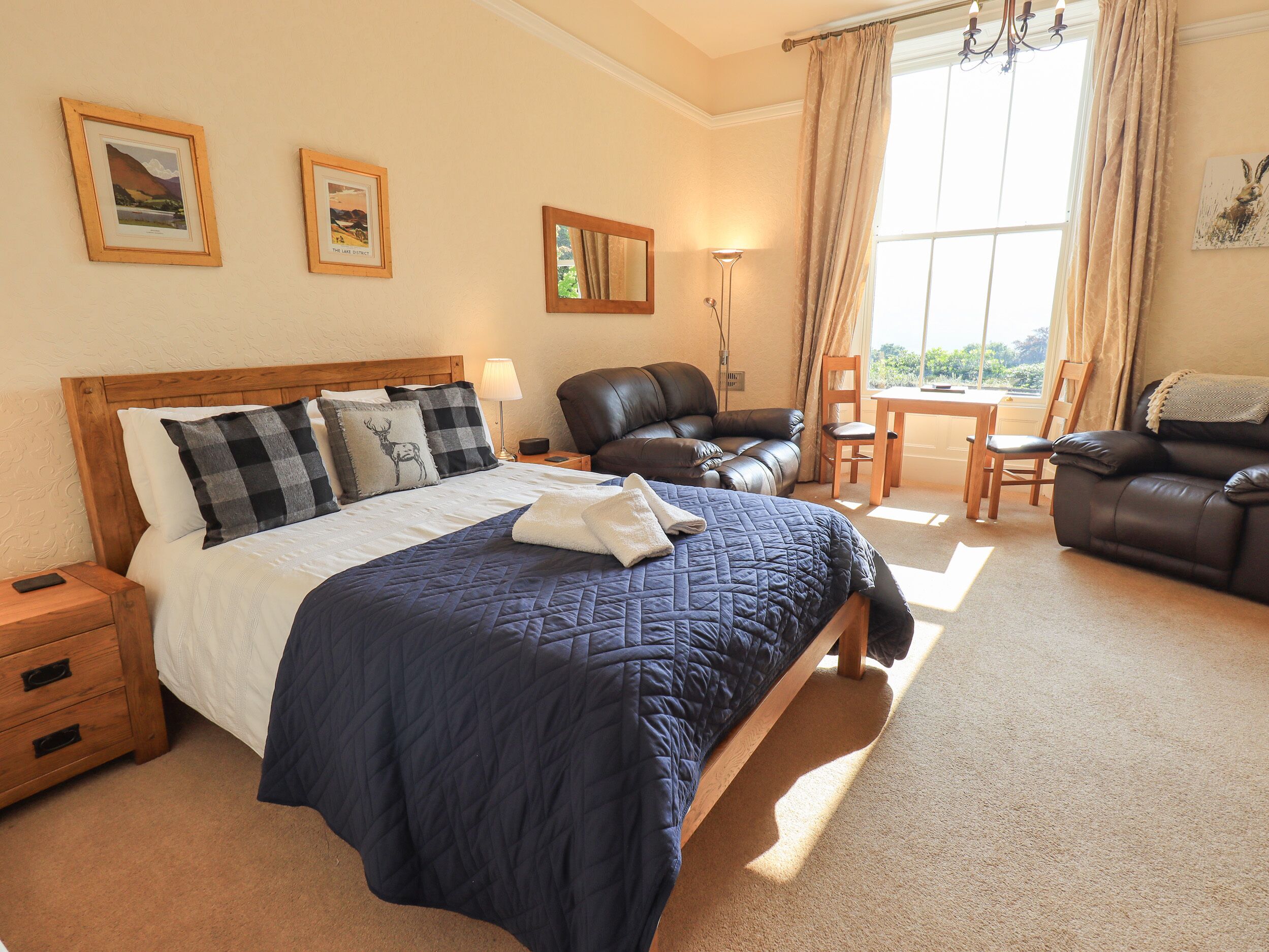 A well-lit bedroom with a large bed, a leather sofa, and a dining table.