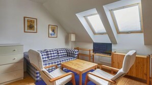 A cozy attic room with a checkered sofa, wooden table, and two chairs. There are skylights and a radiator on the wall. - Skylight Escape by Interhome (Harrachov)