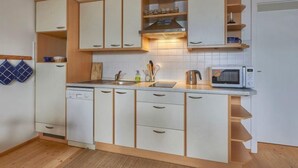 A compact kitchen with white cabinets, a microwave, and a sink. - Skylight Escape by Interhome (Harrachov)