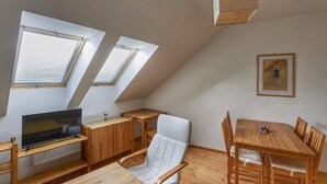 A modern loft bedroom with skylights, a flat-screen TV, wooden furniture, and a framed artwork on the wall. - Skylight Escape by Interhome (Harrachov)