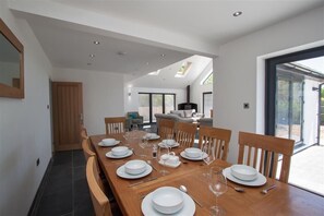 Comedor con una larga mesa de madera dispuesta para seis comensales, rodeada de sillas de madera.