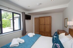 Un dormitorio con cama, armario, ventana y mesita de noche.