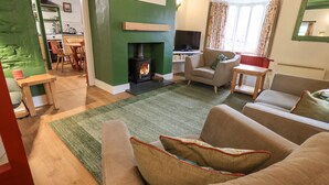 A cozy living room with a fireplace, comfortable seating, and a dining area. - North Lodge (Ambleside)