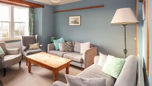 Ein Wohnzimmer mit einer Sofagarnitur, einem Holztisch und einer Stehlampe.