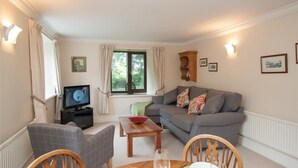 A cozy living room with a grey sofa, a wooden coffee table, and a television on a black stand. - Over Ghyll (Ambleside)