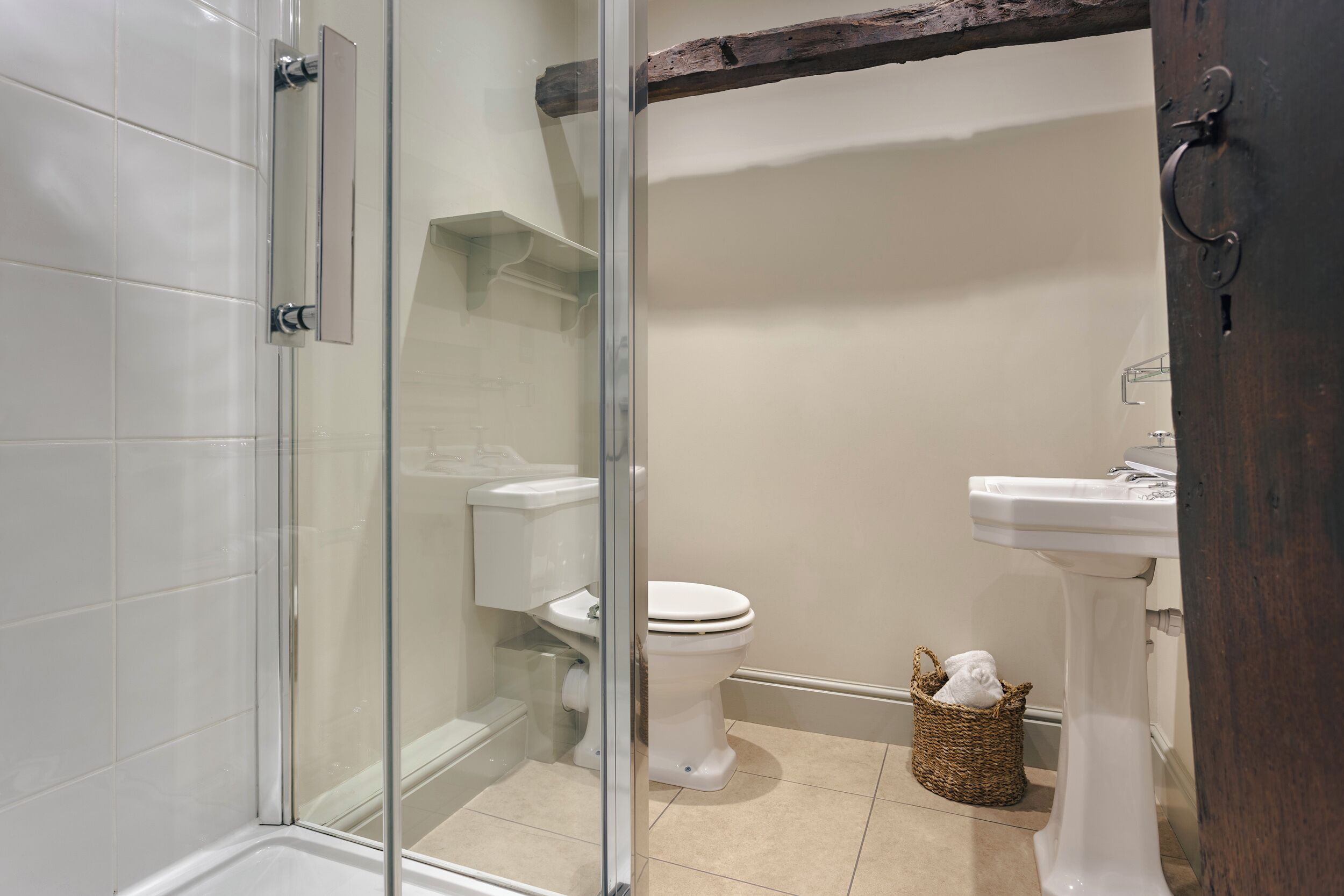 A bathroom with a glass shower enclosure, a toilet, and a pedestal sink.