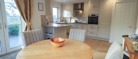 Een moderne keuken met witte kasten, een centraal eiland en een eethoek met een ronde tafel en stoelen.