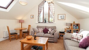 A cozy loft-style living room with a high ceiling, a dining area, and a bookshelf. - Squirrel Bank (Ambleside)