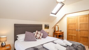 A bedroom with a bed, bedside tables, a dresser, a mirror, and a wardrobe. - Squirrel Bank (Ambleside)