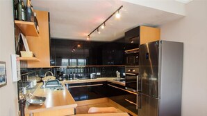 A modern kitchen with a central island, stainless steel appliances, and wooden cabinetry.