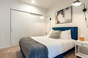 A bedroom with a bed, bedside tables, a wardrobe, and a painting on the wall.