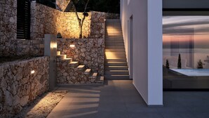 A modern building with a stone facade, a staircase leading to an upper level, and a well-lit entrance area. - The Sall Villa - 2 Bedrooms with Private Pool & Sea View (Volimes)